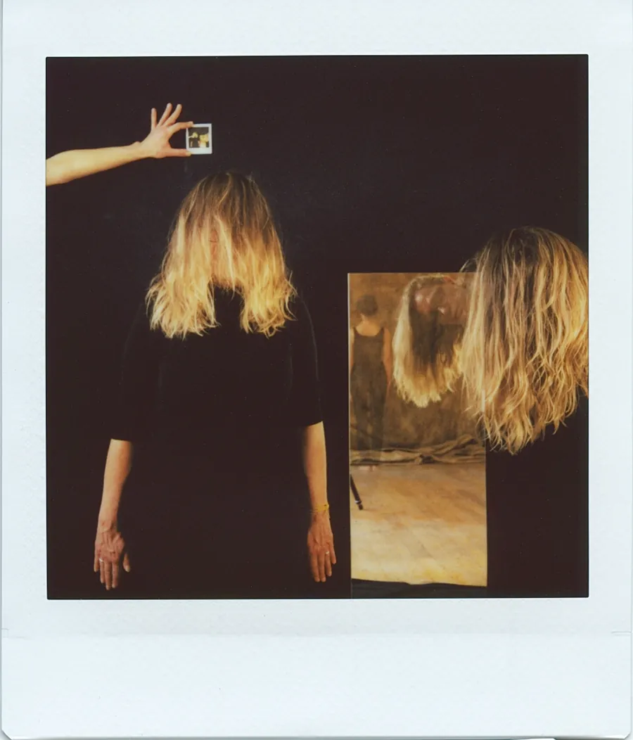 Polaroid : une silhouette de dos, les cheveux blonds retombant, devant un miroir